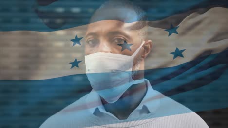 Animation-of-flag-of-honduras-waving-over-man-wearing-face-mask-during-covid-19-pandemic