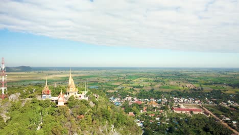 Phnom-Sampov,-Goldene-Buddhistische-Pagode-Auf-Einer-Klippe-Mit-Blick-Auf-Die-Flachen-Ebenen-Grüner-Reisfelder-In-Battambang,-Kambodscha