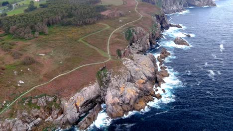 aerial drone shot of a narrow path over an area called paper cliffs with steep cliffs in morás, xove, lugo, galicia, spain at daytime