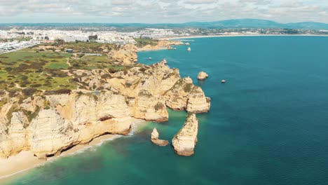 sweeping view over rugged sandstone cliffs lining lagos coast, algarve, portugal - aerial high wide panoramic shot