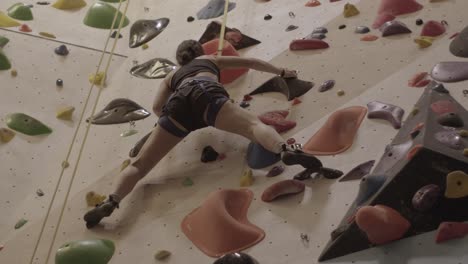 Vista-De-ángulo-Bajo-De-Una-Mujer-Atlética-Trepando-A-La-Pared-En-Un-Gimnasio