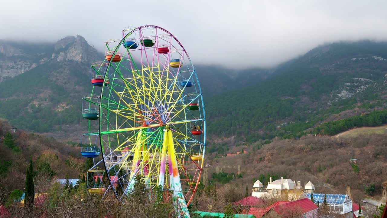 колесо обозрения на фоне гор и лесов в ялте