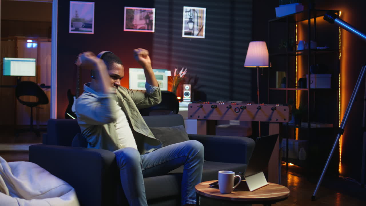 Vertical Video African American guy working on laptop celebrating achievement under neon lights