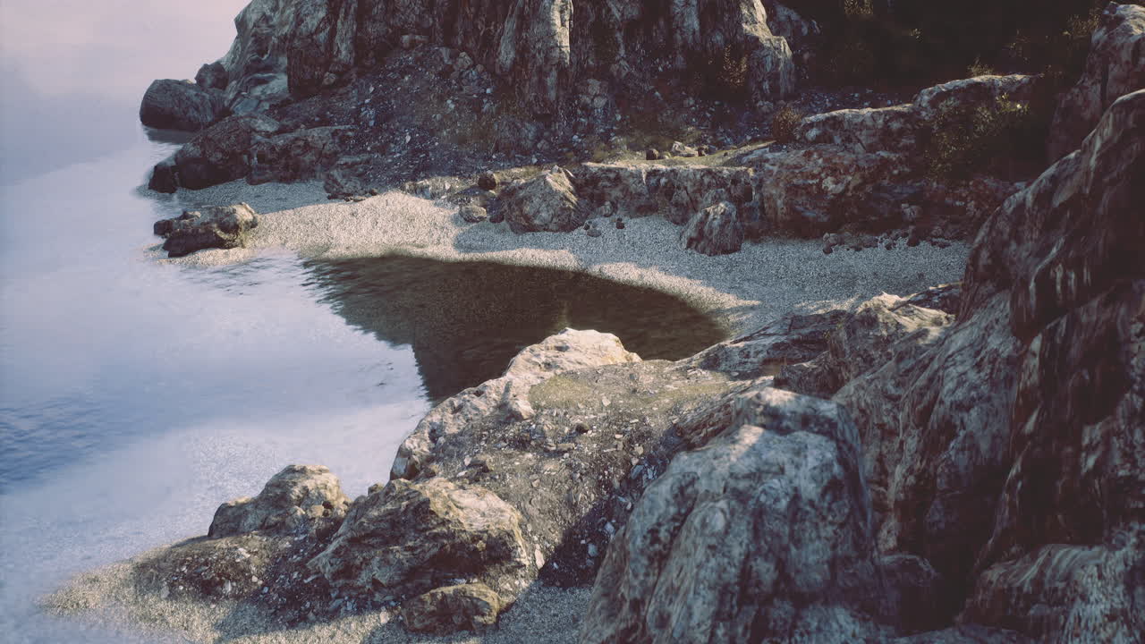 Rocky shoreline with calm water and sandy beach during daytime