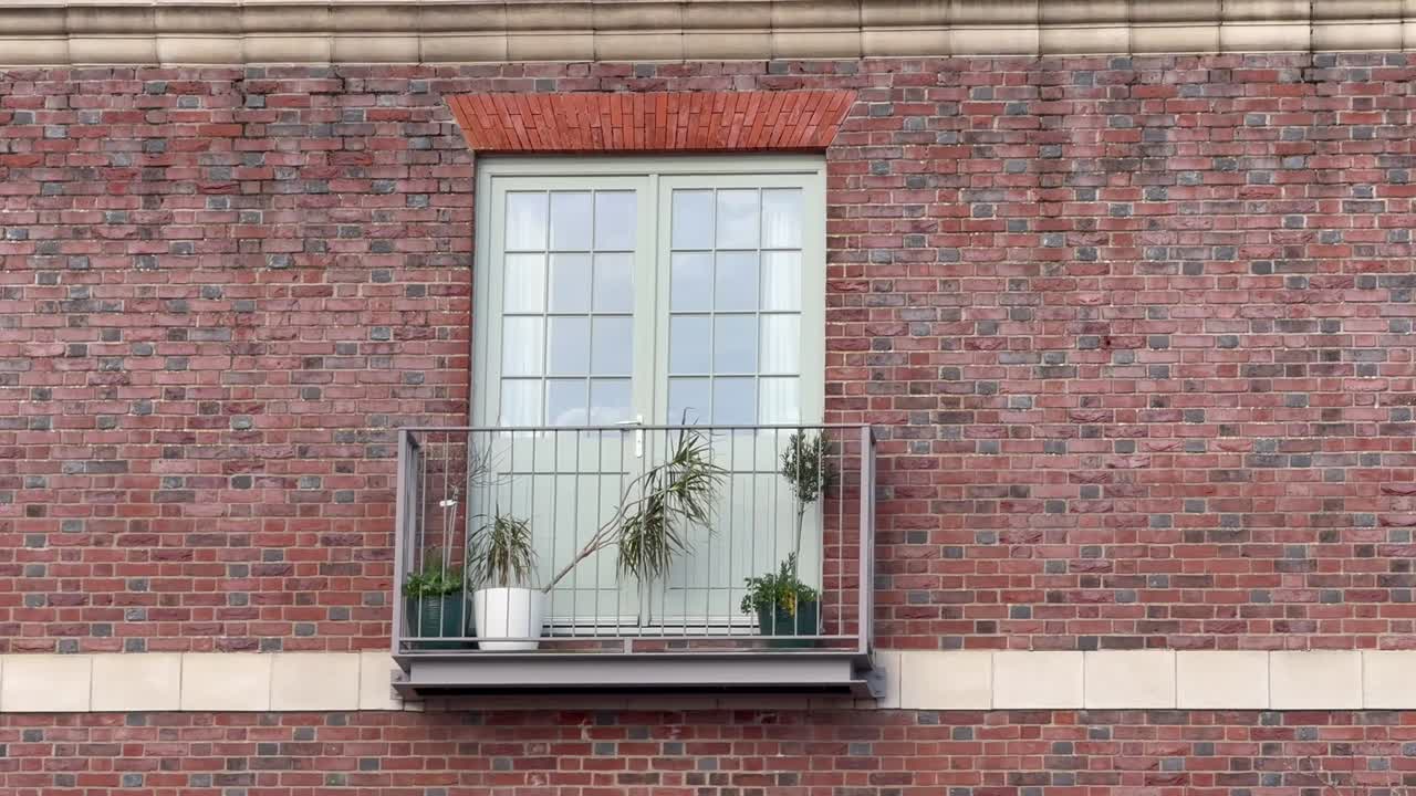 Lille altan med potteplanter på en rød murstensfacade på en lejlighed.