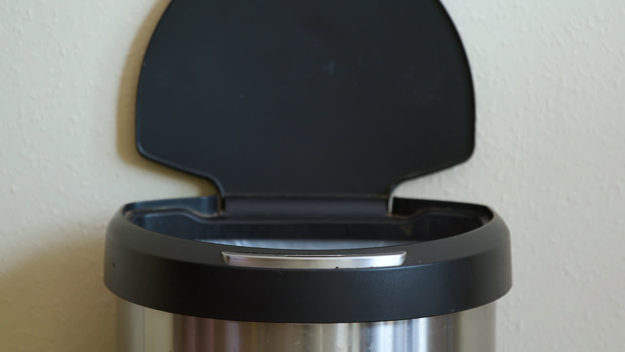 Uomo getta un tovagliolo di carta in una pattumiera automatica con sensore di movimento - Primo piano.