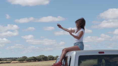 Mujer-Contenta-Tomando-Selfie-En-El-Techo-Del-Coche.