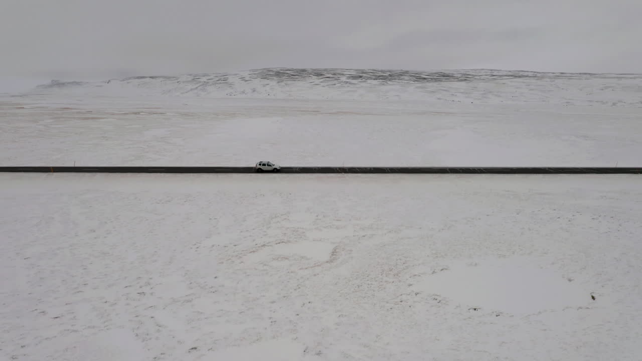 aéreo: siguiendo un coche desde el lado derecho, conduciendo en una carretera nevada