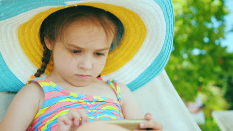 Linda-Chica-En-Un-Sombrero-Juega-En-Un-Teléfono-Inteligente-Descansando-Después-De-Nadar-En-La-Piscina