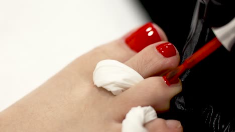 pedicure detail: applying red nail polish to toenails close-up