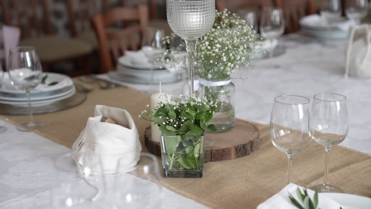 Decorated dining table with floral centerpiece plates glasses napkins and chairs