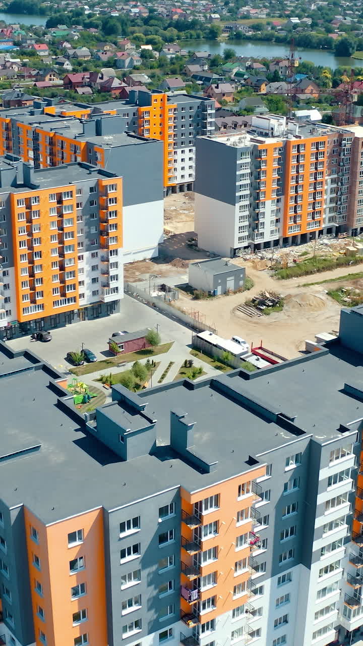 High-rise apartment buildings in the countryside. New complex of modern apartment buildings near the river. Multi-storey housing. Aerial view. Rising up. Vertical video