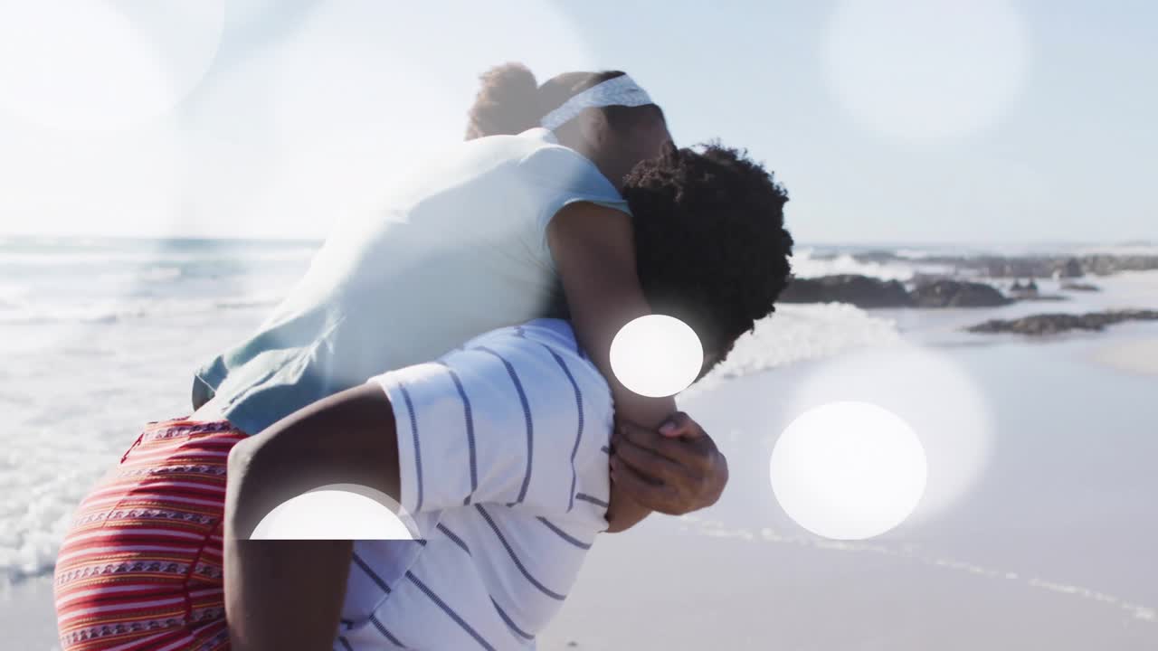 Man lifting woman onto shoulders initiating beach tourism with animated lens flares around couple