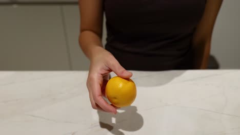 person juggling an orange in the kitchen