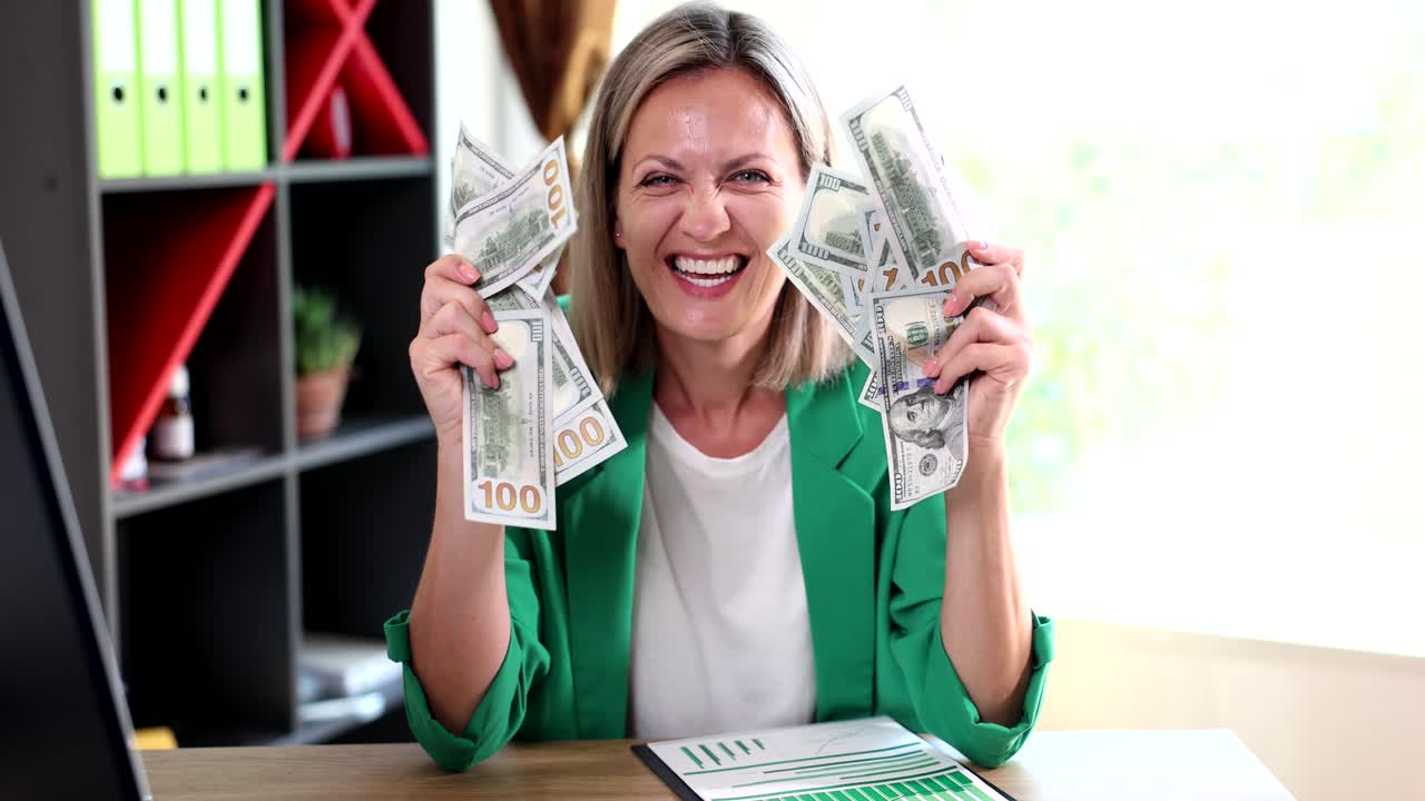 Mujer celebrando con montones de billetes de cien dólares