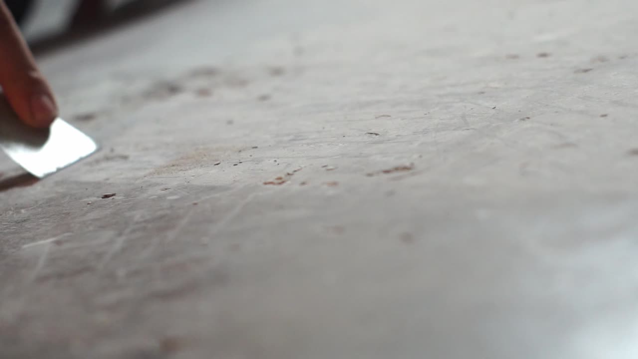 Slow-motion scraping of debris from a marble floor with a spatula