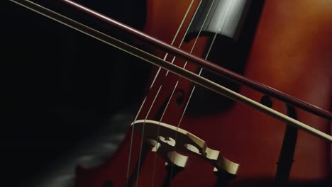 mujer blanca tocando el violonchelo en primer plano de las manos. el arco se mueve lentamente a lo largo de las cuerdas del violonchello. concierto sinfónico, tocando un instrumento