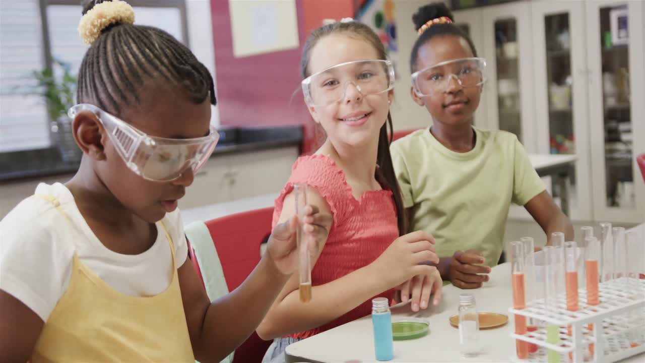 niñas felices y diversas haciendo experimentos en la clase de química de la escuela primaria, en cámara lenta