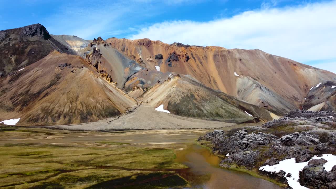 barranco con un río nublado que fluye entre el magma negro y las coloridas montañas arcoiris de landmannalaugar en islandia