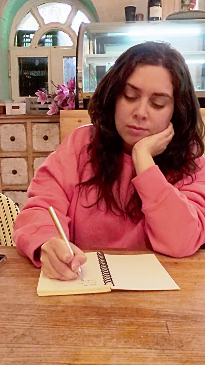 Young woman writing in notebook at cafe table