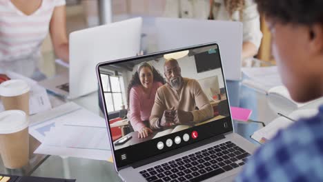 African-american-woman-using-laptop-for-video-call,-with-diverse-business-colleagues-on-screen