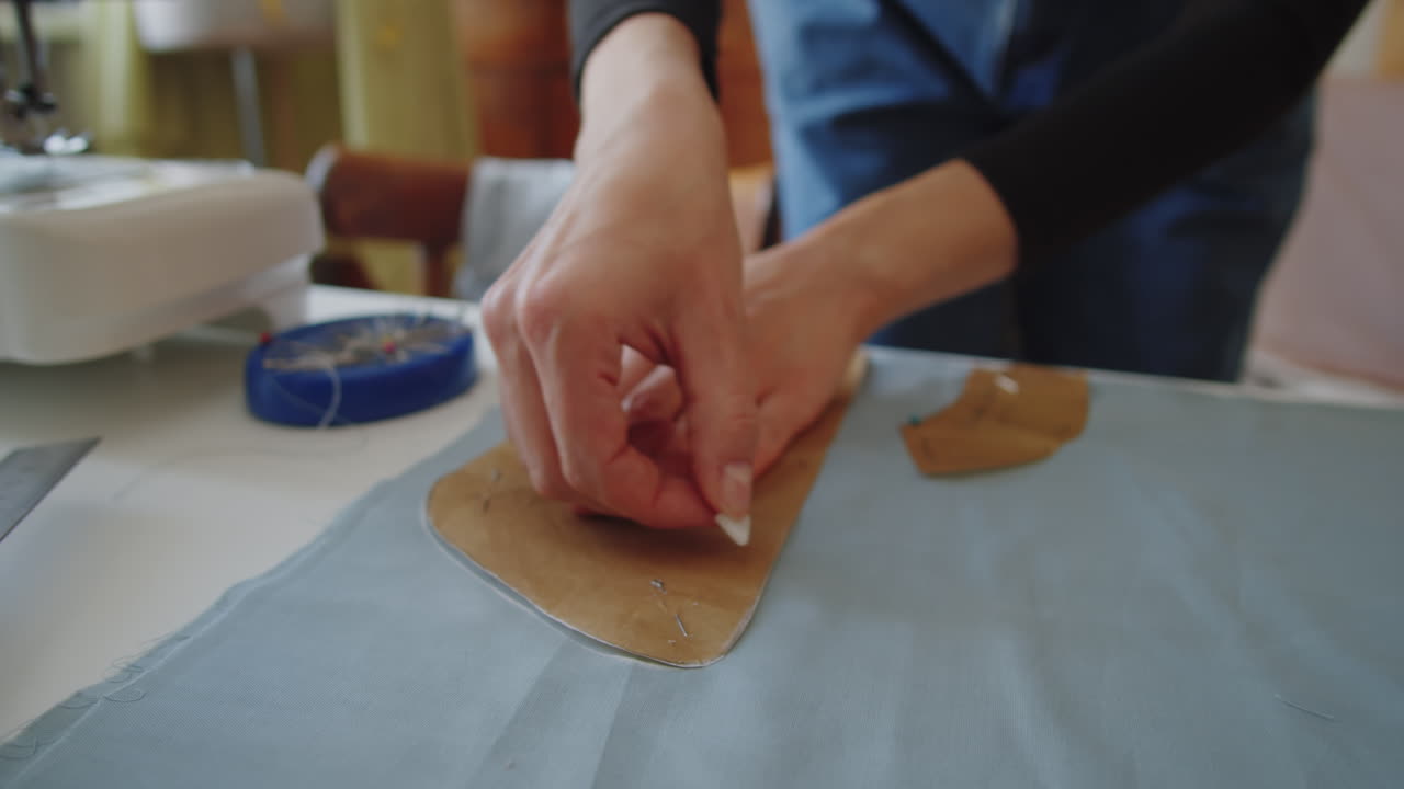 Hands of Dressmaker Outlining Sewing Pattern on Fabric with Chalk