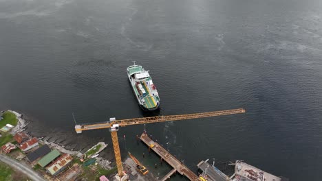 Ferry-Haroy-from-Fjord-1-company-departing-Eidsdal-ferry-pier-and-heading-to-Linge-in-western-Norway---High-angle-aerial-showing-departure-of-ferry-and-construction-work-on-quay