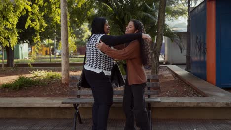 two women having a friendly conversation and sharing shopping bags and coffee in a park