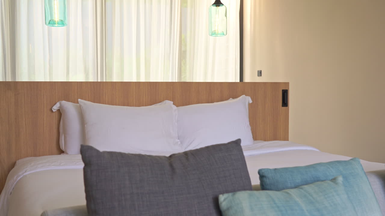 Tilt-down from bed to close up of couch filled with colorful decorative pillows.