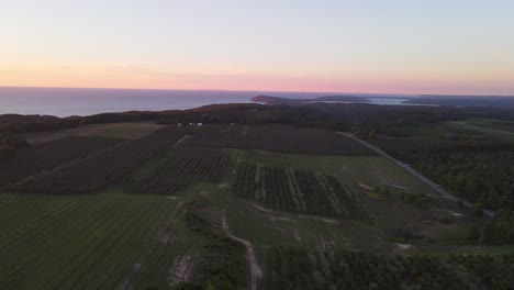 Sobrevuelo-Aéreo-De-Las-Tierras-De-Cultivo-En-La-Península-De-Leelanau-Cerca-Del-Parque-Nacional-De-Dunas-De-Osos-Durmientes-Y-La-Orilla-Del-Lago-Nacional-Al-Atardecer