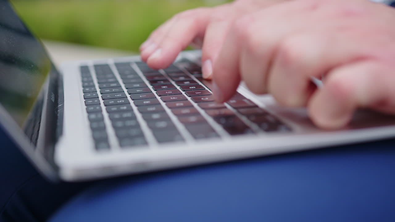 A businessman in a blue suit sits with a laptop in front of the office building close-up
