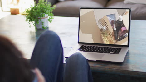 Knees-of-woman-at-table-using-laptop,-online-shopping-for-beauty-products,-slow-motion