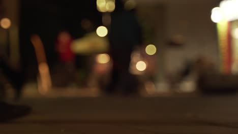 people's feet walking on promenade at night with blurry background of city lights