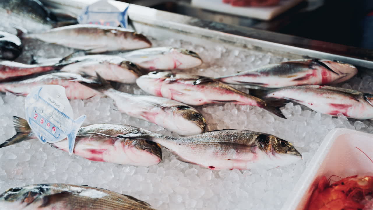 Close up shot of fresh whole fish neatly arranged on a bed of crushed ice at a seafood market, highlighting their shiny scales and premium quality