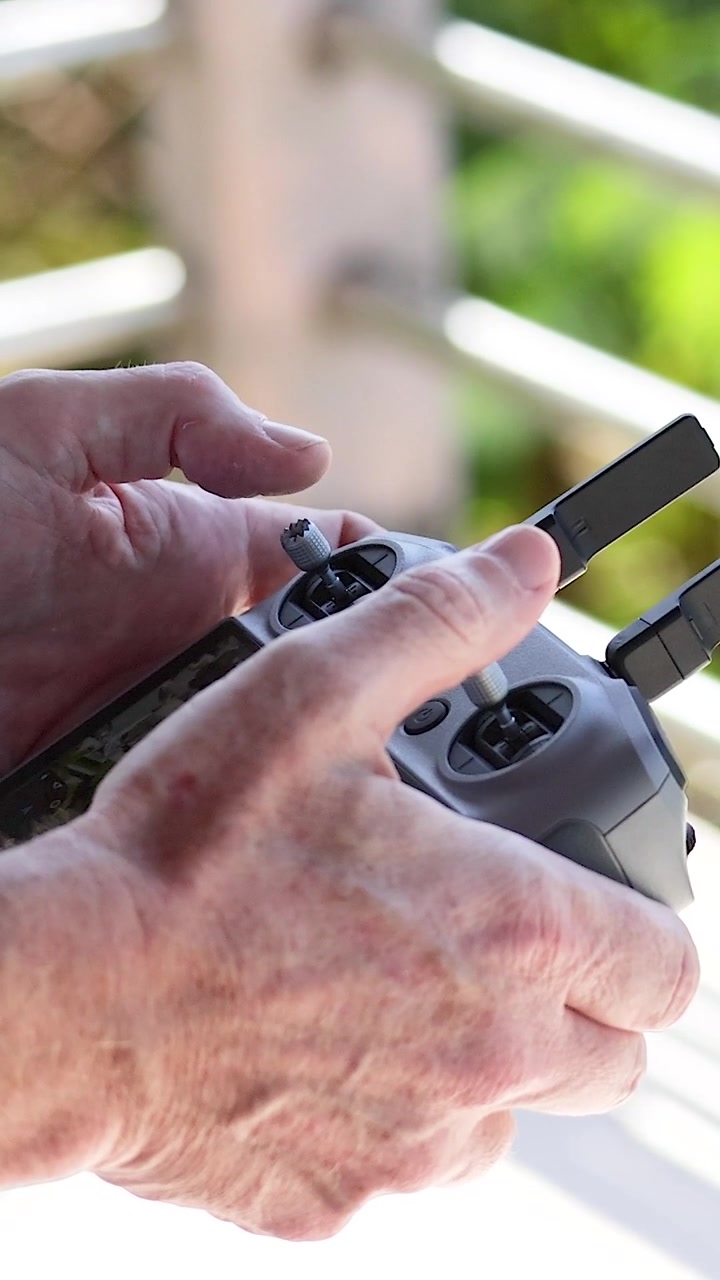 Un primo piano dettagliato di mani che manipolano abilmente i joystick su un moderno telecomando