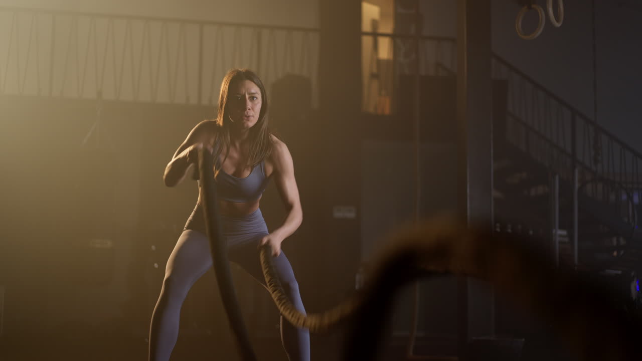 Woman exercising with battle ropes in a gym