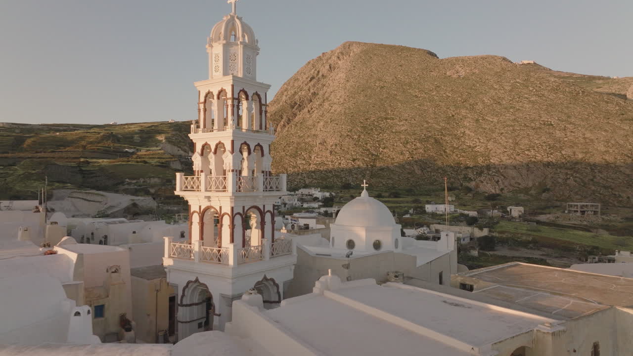 해가 뜨고 해가 지는 동안 그리스 마을 교회 와 종탑 의 공중 사진