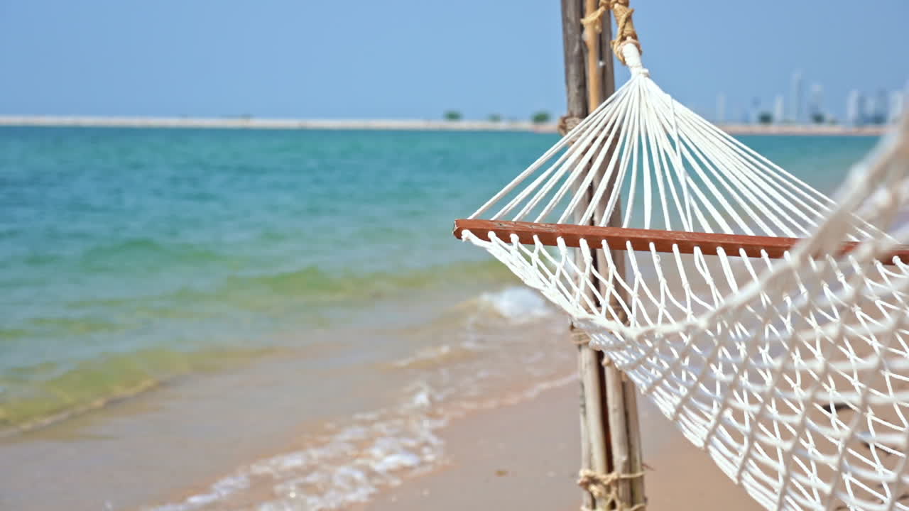 hamaca vacía en la playa y la costa en segundo plano.