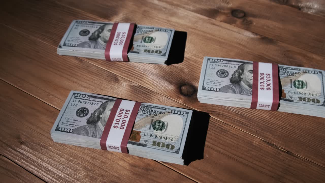 Three Stacks of 10000 American Dollars Banknotes in Bundles Lie on Wooden Table