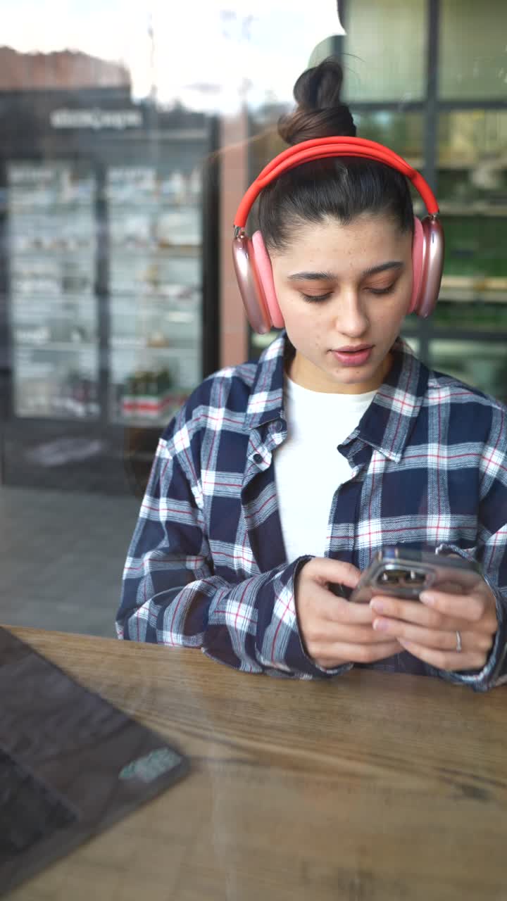 mujer en un café con auriculares y teléfono