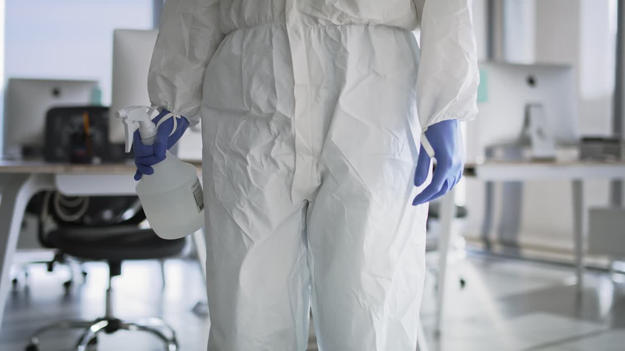 video de una persona irreconocible con ropa de trabajo protectora con botella de aerosol