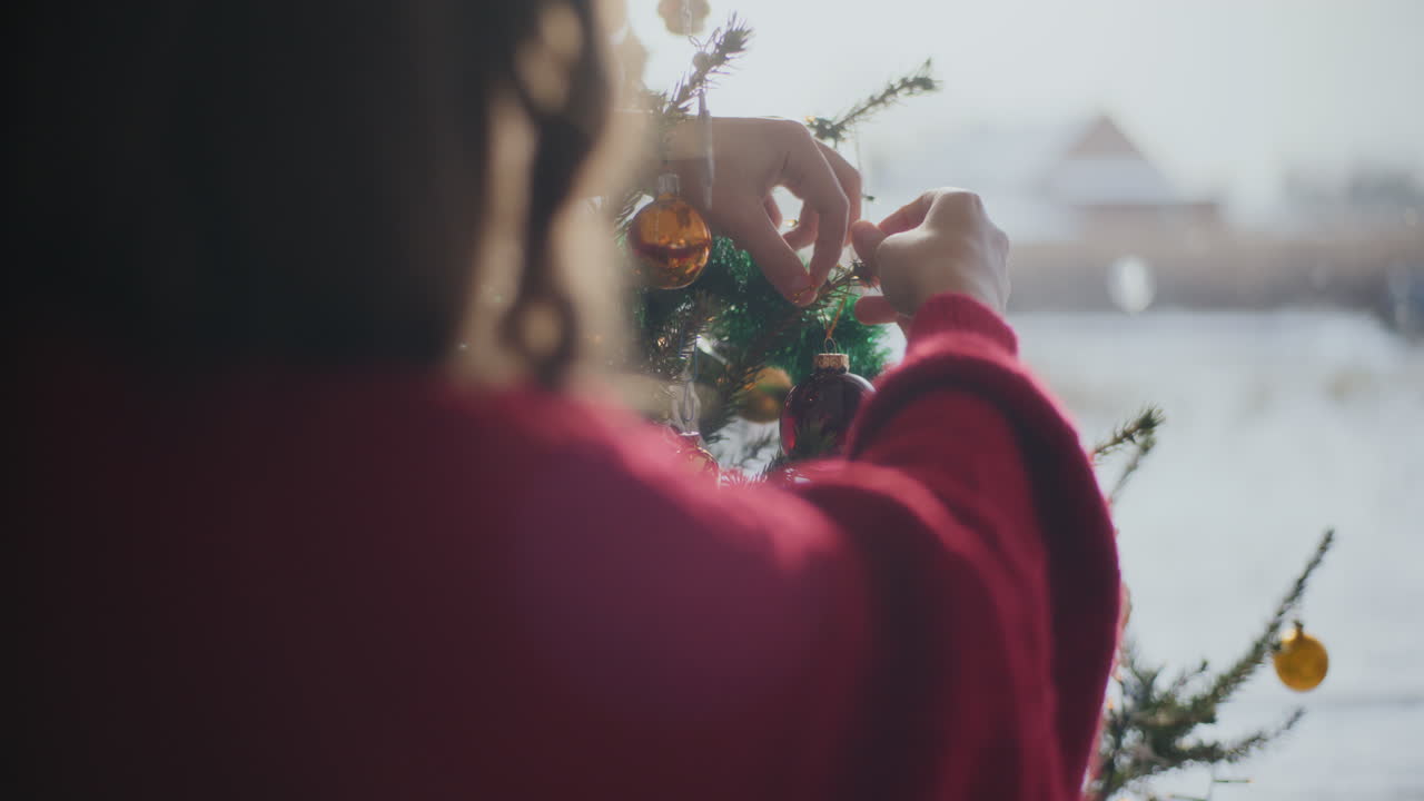 밝은 집에서 bauble와 함께 크리스마스 트리를 장식하는 절단 된 여성