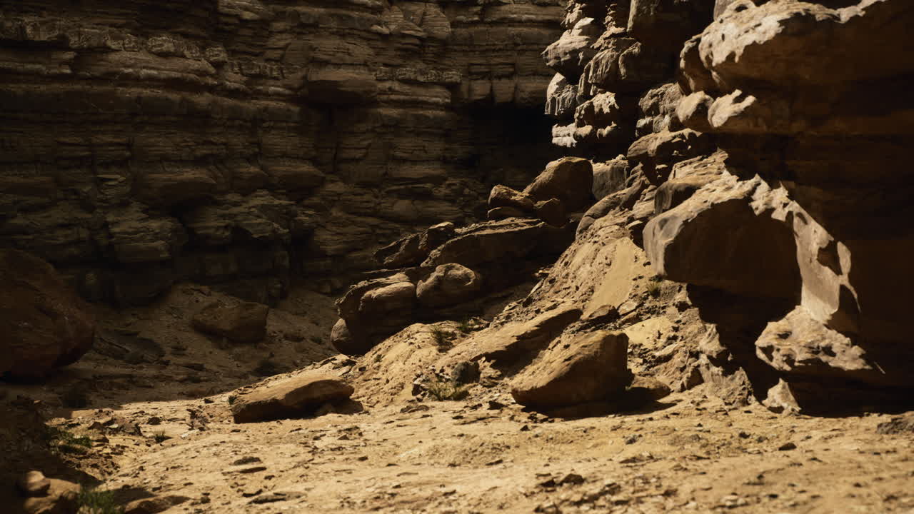 Rock formations and sandy terrain in a secluded canyon during daytime