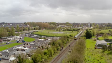 Train-leaves-along-railway-commuting-across-countryside-near-Tullamore-Ireland