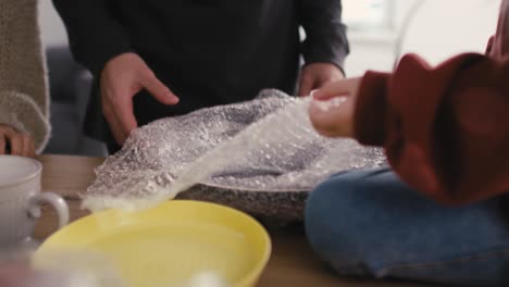 Close-up-of-family-human-hands-packing-kitchen-stuff-while-moving-house.