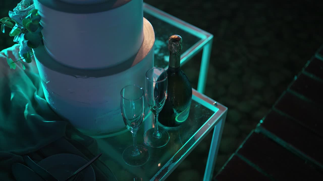 결혼 케이크와 페인 컵은 우아하게 배열되어 있으며, 부드러운 조명 아래 축하 토스트를 준비하고 있습니다.