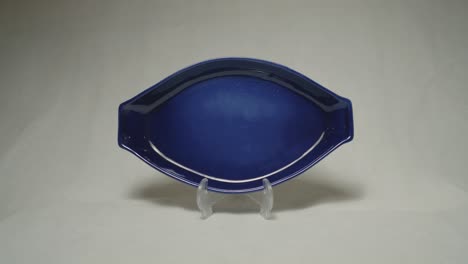 closeup shot of a blue artifacts on a stand against a white background.