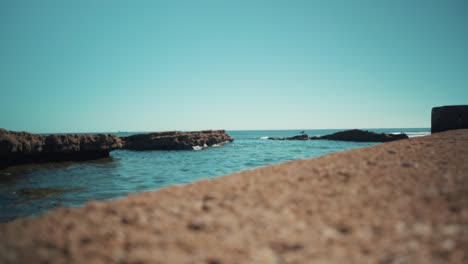 Ocean-shoreline-flat-waves-hit-rocks-at-sunshine-with-seagul-4K