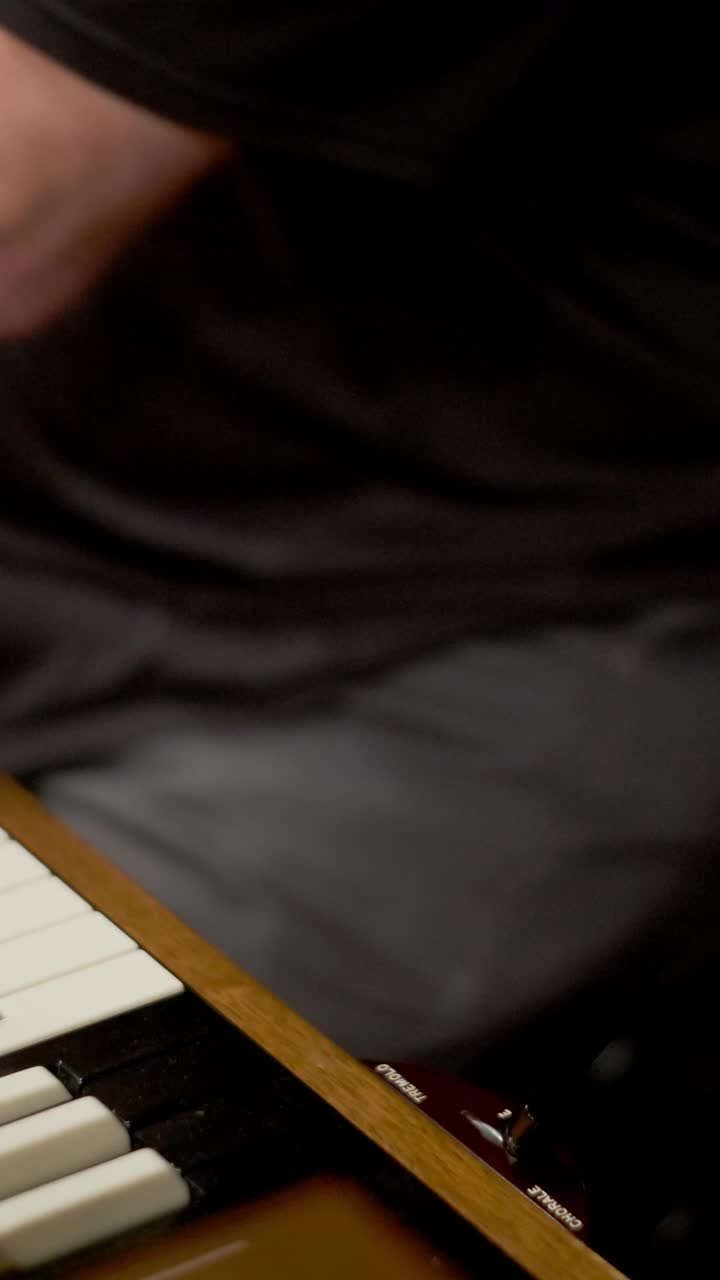 Vertical - Cropped Portrait Of Man Playing Organ Keyboard, Adjusting Lever With One Hand As Thigh Shifts While Stomping On Foot Pedal Below. closeup shot