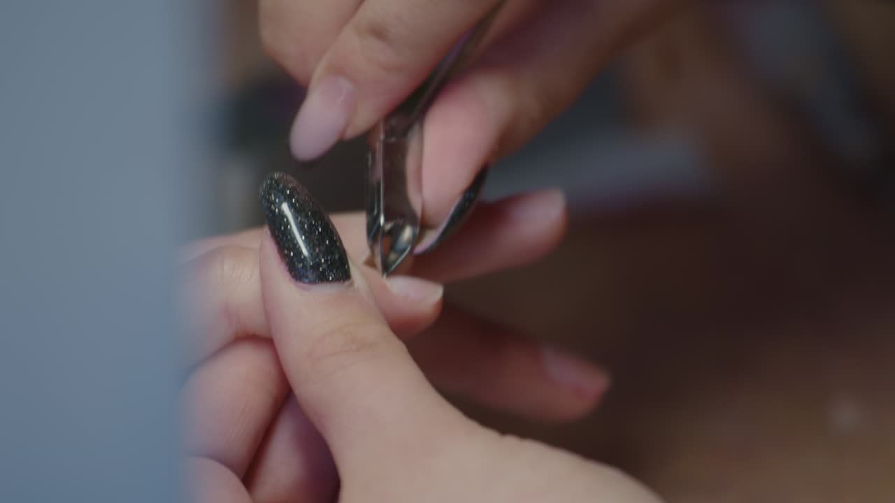 manicurista cortando las uñas del cliente usando un cortador de cutículas